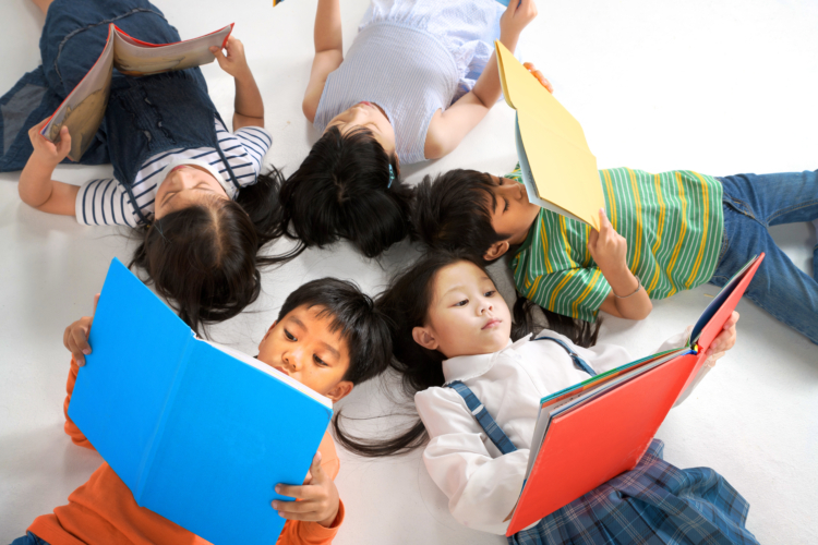 Kids reading book laying on the white floor , head to head, in a circle group, preschool library, Kindergarten school education concept